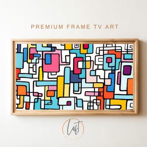 May include: Abstract geometric art print with a white background and colorful squares and lines in shades of blue, pink, yellow, orange, and red. The print is framed in a light wood frame.