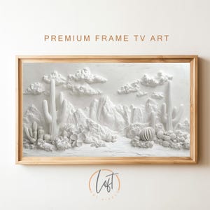 以下が含まれることがあります： 山、雲、サボテンが描かれた白い3D壁アート。明るい木製のフレームで囲まれています。