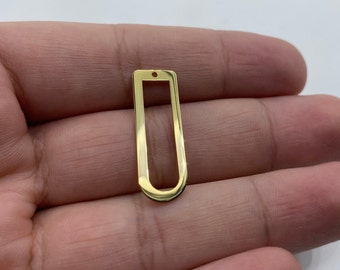 Puede incluir: Pendiente de metal dorado con forma rectangular y un pequeño agujero en la parte superior para sujetar una cadena o cordón.