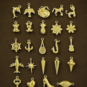 Puede incluir: Una colecci&oacute;n de dijes dorados en varias formas, incluyendo un delf&iacute;n, un p&aacute;jaro, un cisne, un caballo, un oso de peluche, una pi&ntilde;a, una flor, un tim&oacute;n, un ancla, una raqueta de tenis, un saxof&oacute;n, una guitarra, un avi&oacute;n, una estrella y un zapato de tac&oacute;n.