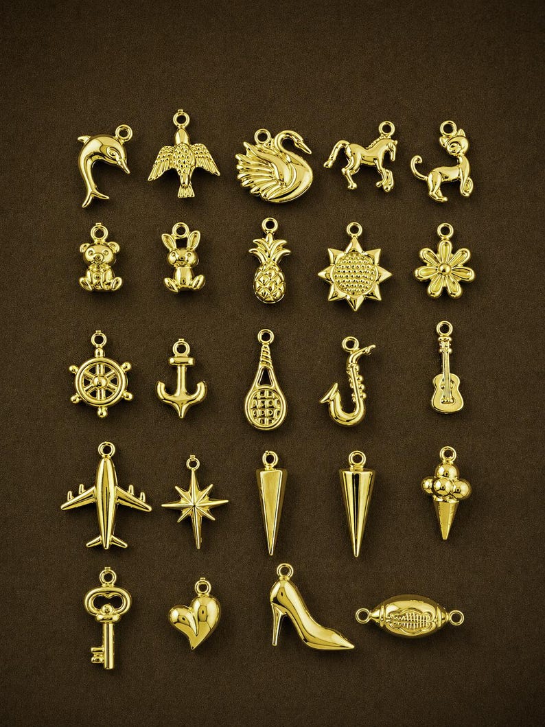 Puede incluir: Una colecci&oacute;n de dijes dorados en varias formas, incluyendo un delf&iacute;n, un p&aacute;jaro, un cisne, un caballo, un oso de peluche, una pi&ntilde;a, una flor, un tim&oacute;n, un ancla, una raqueta de tenis, un saxof&oacute;n, una guitarra, un avi&oacute;n, una estrella y un zapato de tac&oacute;n.