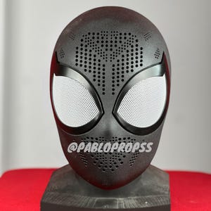 May include: Black Spider-Man mask with a white mesh eye design and a dotted pattern. The mask is on a black stand. @PABLOPROPSS