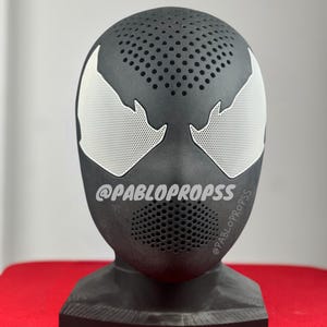 May include: Black and white 3D printed Venom mask with a textured surface and a white logo that reads "@PABLOPROPSSS".