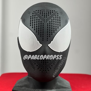 May include: Black Spider-Man mask with white eyes and a dotted pattern. The mask is on a black stand. The text "@PABLOPROPSSS" is printed on the mask.