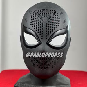 May include: Black Spider-Man mask with a black and white eye design and a black base. The mask has a textured surface with small holes throughout. The text "@PABLOPROPSS" is visible on the mask.