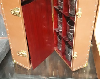 May include: A brown leather-bound box with a red interior and a small drawer. The box is open and reveals six clear glass tumblers.