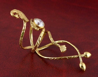 May include: A gold-tone ring with a clear rhinestone and a swirling, vine-like design.