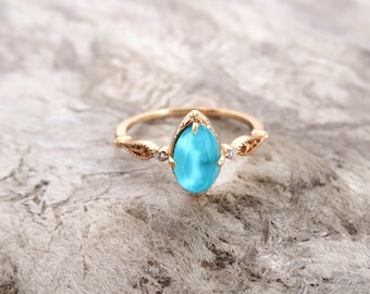 May include: A gold ring with a light blue oval gemstone and two smaller clear gemstones on the band.