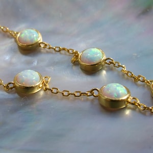May include: A gold chain necklace with white opal stones. The necklace has a delicate chain and round opal stones.