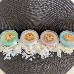 May include: Four small round containers of wax melts with a thank you label on each. The wax melts are in the colours green, beige, brown, and blue.