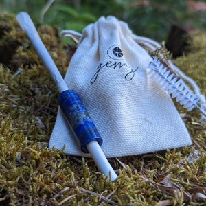 Peut inclure: Un sac en toile blanc avec le mot "gem" imprimé dessus, un papier à rouler blanc et une pipe bleue et blanche avec un accent en pierre précieuse bleue.
