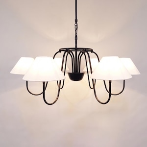 May include: A black metal chandelier with six white lampshades. The lampshades are cone-shaped and evenly spaced around the central fixture. The chandelier hangs from a single chain.