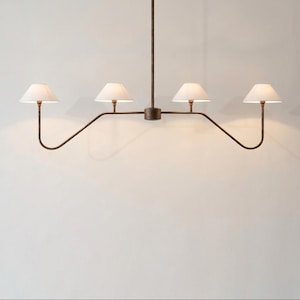 May include: A modern chandelier with four lights. The fixture has a dark brown metal frame with four curved arms, each holding a white lampshade. The lampshades are conical and emit a warm glow. The chandelier hangs from a single rod.