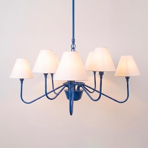 May include: A blue chandelier with six white lampshades. The fixture has a central stem and curved arms extending to hold the shades. The lampshades are cone-shaped, and the fixture is against a white background.