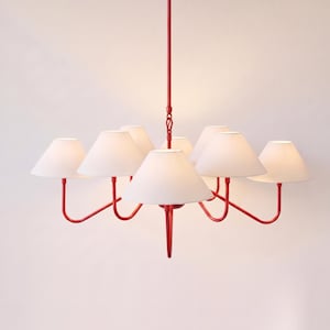 May include: A bright red metal chandelier featuring a central vertical rod and multiple curved arms extending outward. Each arm supports a white, cone-shaped fabric lampshade, creating a symmetrical lighting fixture with a bold, colorful frame.