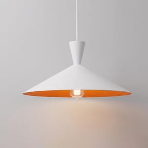 Può includere: Una lampada a sospensione con un ampio paralume conico, caratterizzato da un esterno bianco opaco e un interno arancione vivace. L'apparecchio è sospeso da un sottile cavo bianco e include una lampadina a vista sotto il paralume.
