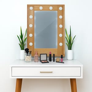 May include: A white vanity table with a wooden-framed mirror featuring light bulbs. The table holds makeup, brushes, and potted plants. The mirror is rectangular and the table has a drawer with a gold handle.