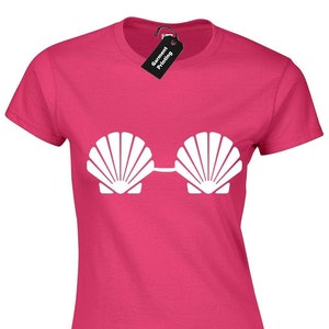 May include: A pink t-shirt featuring a white seashell graphic. The seashells are arranged to resemble a pair of sunglasses.