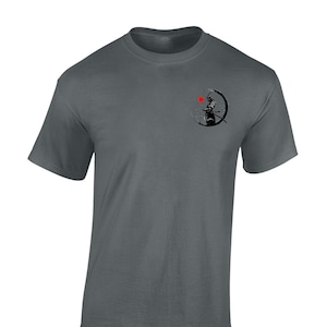 May include: A dark grey t-shirt featuring a black and white graphic of a samurai warrior standing in front of a red sun. The graphic is on the left side of the shirt.