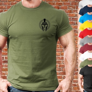 May include: A green short-sleeved t-shirt with a black Spartan helmet graphic on the front. The helmet is inside a circle with a Greek key design.