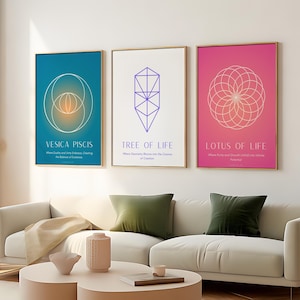 Op de afbeelding: Drie ingelijste kunstprints met gouden randen. De prints tonen geometrische ontwerpen en de tekst: "VESICA PISCIS", "TREE OF LIFE" en "LOTUS OF LIFE". De achtergronden zijn teal, wit en roze. De prints worden weergegeven boven een witte bank met groene kussens.