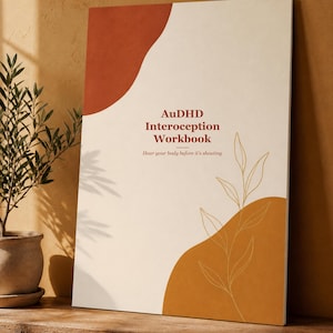 Può includere: Un quaderno di esercizi rettangolare con una copertina color crema caratterizzata da forme astratte color terracotta e senape. Il testo recita AuDHD Interoception Workbook e Hear your body before it's shouting, con un sottile disegno a linee dorate di una pianta.