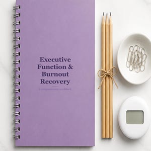 Può includere: Un quaderno di esercizi a spirale color lavanda intitolato Executive Function & Burnout Recovery: A compassionate workbook, accompagnato da tre matite in legno chiaro legate con spago, una piccola ciotola bianca di graffette argentate e un timer digitale bianco.