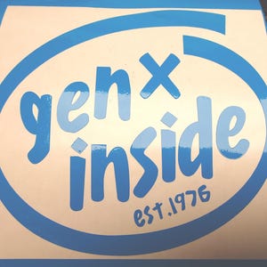 Könnte beinhalten: Ein blau-weißer Aufkleber mit dem Text "genX inside" in einer stilisierten Schriftart, umgeben von einem blauen Oval. Der Text "est.1976" befindet sich unten. Der Aufkleber befindet sich auf weißem Hintergrund.