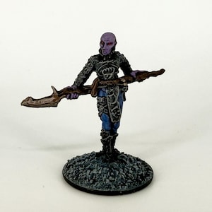 May include: A miniature fantasy figure of a humanoid creature with purple skin, red eyes, and intricate armor. The figure holds a brown, curved weapon and stands on a textured, gray base. The figure's clothing is detailed with blue and black accents.
