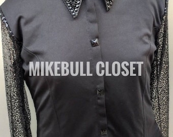 Puede incluir: Una camisa negra de manga larga con cuello y mangas de lentejuelas. El cuello está adornado con adornos negros y plateados. La camisa tiene un frente abotonado y el texto "MIKEBULL CLOSET" está impreso en el frente.