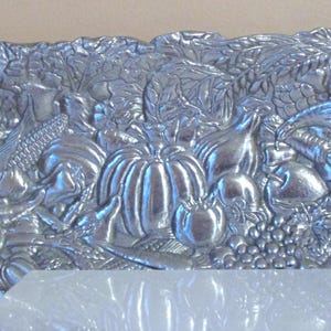 May include: A silver serving tray with a raised design of a cornucopia overflowing with fruits and vegetables. The tray is made of metal and has a shiny finish.