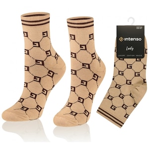 May include: A pair of beige socks with a brown geometric pattern. The socks have a brown stripe at the top and are made of cotton. The socks are shown on a white background.