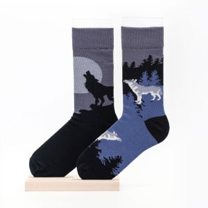 May include: A pair of grey and blue socks with a wolf howling at the moon design. One sock has a black wolf howling at the moon, and the other sock has a white wolf howling at the moon.