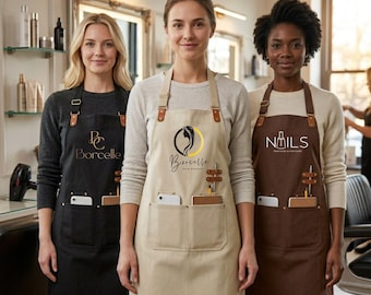 Könnte beinhalten: Drei Schürzen in Schwarz, Beige und Braun, jeweils mit verstellbaren Trägern mit Lederakzenten, zwei Vordertaschen und einem Stiftehalter. Die schwarze Schürze zeigt 'BC Borcelle', die beige 'Borcelle Hair Beauty' und die braune 'Nails'.