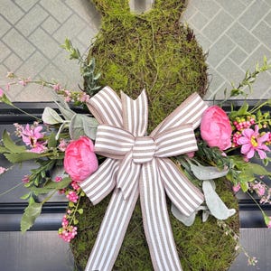 Pu&ograve; includere: Una ghirlanda a forma di coniglio ricoperta di muschio, con un fiocco a righe e fiori rosa. La ghirlanda &egrave; decorata con peonie rosa finte, piccoli fiori rosa e fogliame verde, perfetta per Pasqua o la primavera.