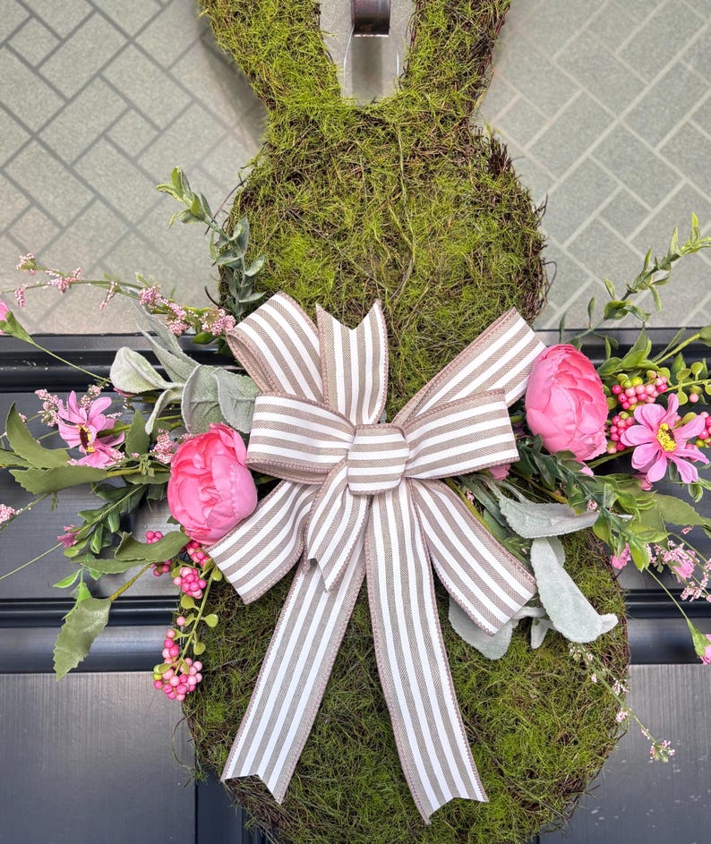 Pu&ograve; includere: Una ghirlanda a forma di coniglio ricoperta di muschio, con un fiocco a righe e fiori rosa. La ghirlanda &egrave; decorata con peonie rosa finte, piccoli fiori rosa e fogliame verde, perfetta per Pasqua o la primavera.