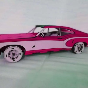 Könnte beinhalten: Ein rosafarbenes und weißes Vintage-Automodell mit einem weißen Streifen an der Seite. Das Auto hat schwarze Räder und einen schwarzen Innenraum.