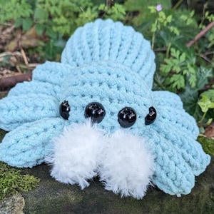 May include: A crocheted blue spider plush toy with white fuzzy legs and black button eyes.