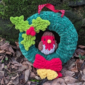 May include: A green yarn wreath with a red bow and a crocheted robin. The wreath is decorated with a green yarn holly sprig.