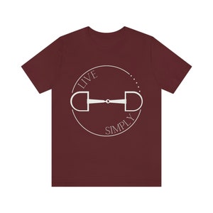 May include: A maroon t-shirt with a white circle graphic featuring a horse bit and the text "LIVE SIMPLY".