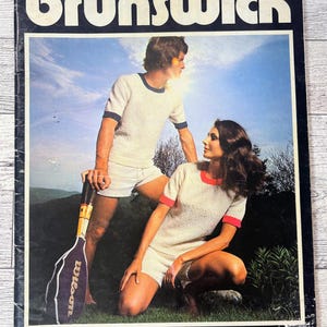 May include: Vintage magazine cover with the word "brunswick" in large white letters. The cover features a photo of a man and woman in tennis attire, with a tennis racket. The text "mostly male" is at the bottom.