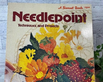 May include: A vintage book titled "Needlepoint: Techniques and Projects" with a colourful needlepoint image of a basket of strawberries and flowers on the cover. The book is a Sunset Book and has the number 5295 on the cover.