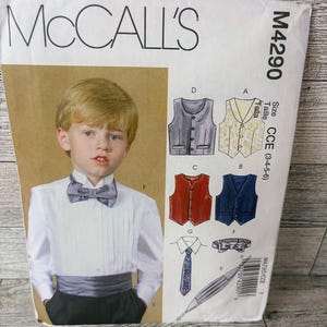May include: A sewing pattern for a boy's outfit, featuring a white shirt with a bow tie, a vest, and a tie. The pattern is from McCall's and is size CCE (3-4-5-6).