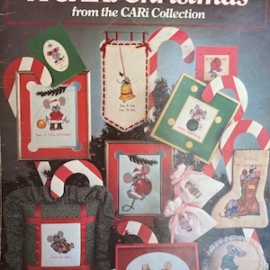 May include: A collection of cross-stitch patterns featuring mice and Christmas themes. The patterns include a mouse holding a bell, a mouse holding a Christmas ornament, a mouse in a stocking, and a mouse with a candy cane. The patterns are framed in red and white candy cane frames.