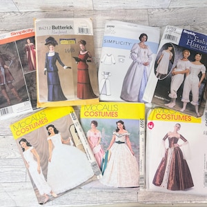 Op de afbeelding: Een verzameling vintage naaipatronen voor kostuums, waaronder merken als Simplicity, Butterick en McCall's. De patronen bevatten illustraties van historische jurken en outfits, met teksten als "COSTUMES" en "The Fashion Historian".