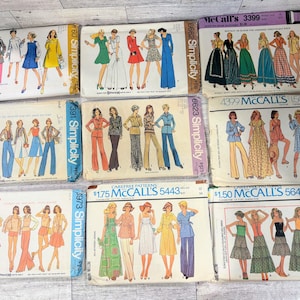 Puede incluir: Una colección de nueve sobres de patrones de costura vintage de Simplicity y McCall's, con varios diseños de ropa que incluyen vestidos, faldas y pantalones. Cada sobre muestra ilustraciones de prendas, logotipos de marcas y números.