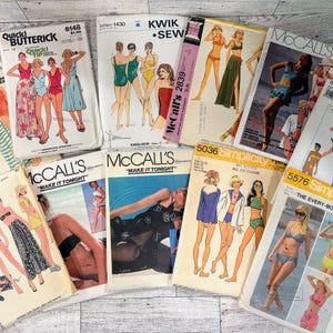 May include: A collection of ten vintage sewing patterns featuring illustrations of swimwear and summer clothing. The paper envelopes display brand names including Butterick, Kwik Sew, McCall's, and Simplicity, with various models wearing bikinis, swimsuits, and cover-ups.