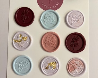 May include: A collection of nine circular wax seals in various colors including burgundy, light blue, lavender, and peach, featuring embossed designs of flowers, a bee, a tree, and the text Thank You, with a logo reading Designs by Ashlyn Rose.
