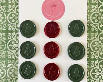 May include: A white card with a pink circle logo that says "Designs by Ashlyn Rose". The card has nine wax seals arranged in three rows. The seals are red and green with a Christmas tree design. The card also has the text "Take time to smell the roses."  Proverb.