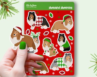 May include: A sheet of stickers featuring Shetland Sheepdogs in various Christmas outfits. The stickers are on a red background with white polka dots. The text "Shetland Sheepdog" is at the top of the sheet.